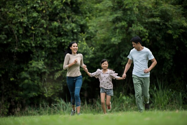 La famiglia felice si diverte Madre, padre e figlia stanno correndo nel parco.