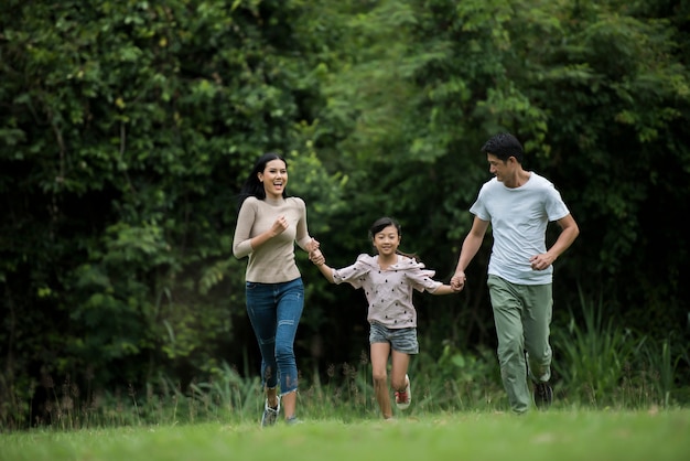 La famiglia felice si diverte Madre, padre e figlia stanno correndo nel parco.