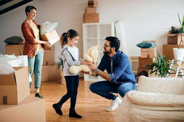 La famiglia felice si diverte mentre porta i propri effetti personali nella loro nuova casa