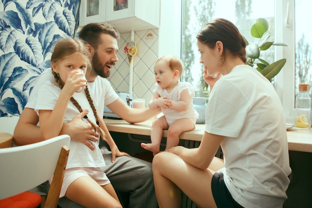 La felice famiglia caucasica sorridente in cucina a preparare la colazione