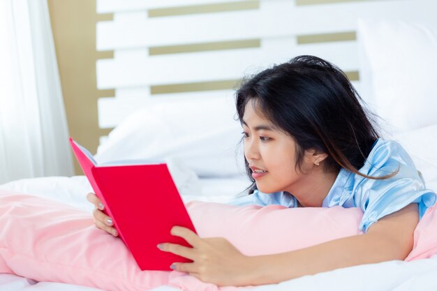 La femmina asiatica dell'adolescente ha letto il libro del diario sul letto