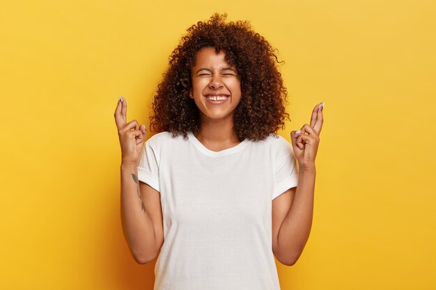 La femmina riccia positiva incrocia le dita