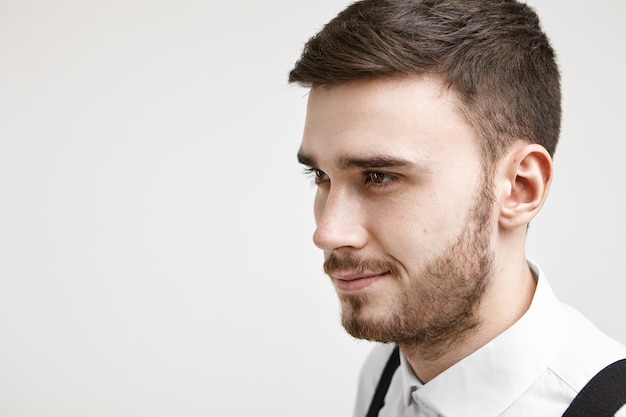 La fiducia in se stessi e il concetto di mascolinità. Ritratto isolato dello studio del giovane impiegato maschio sicuro positivo con taglio di capelli alla moda e stoppie che sorridono mentre ha qualche grande idea riguardo al lavoro