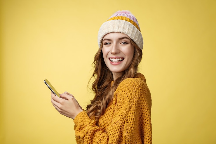 Foto gratuito la foto del profilo ha intrattenuto una giovane donna affascinante che giocava al cellulare con in mano lo smartphone che girava la fotocamera...