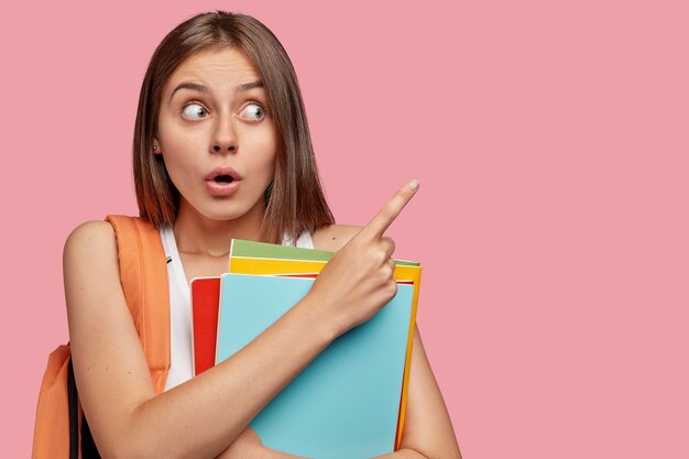 La foto della donna dai capelli scura stupita sorpresa guarda con sorpresa da parte, indica lo spazio della copia