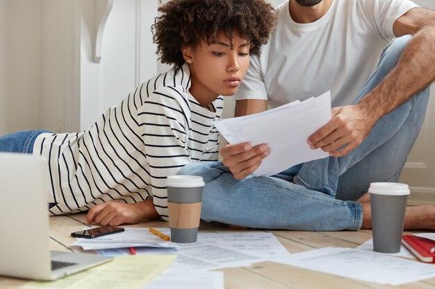 La foto della famiglia multietnica controlla l'equilibrio sui documenti, beve il caffè da asporto, pensa a quanto sia stretto affare