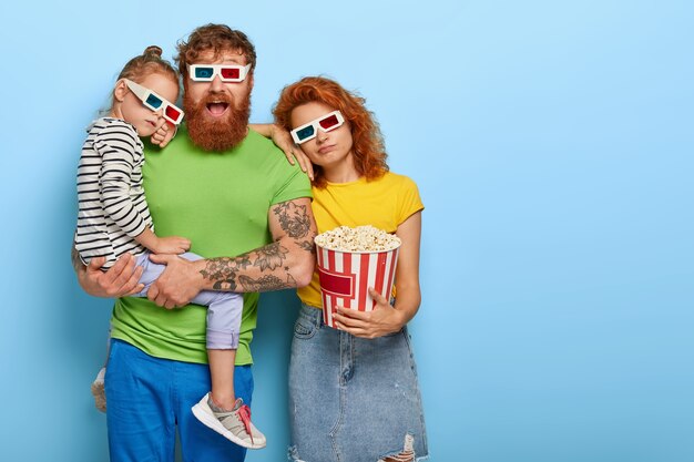 La foto della figlia stanca e della mamma si appoggia al marito che guarda con un'espressione felice impressa, trascorre il tempo libero al cinema, guarda film per lunghe ore, indossa occhiali tridimensionali, mangia popcorn nel secchio