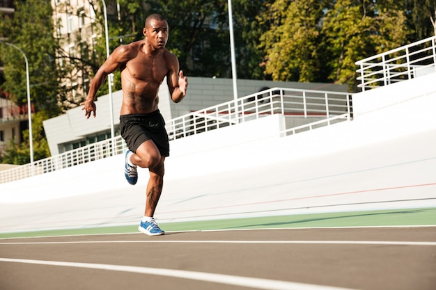 La foto di giovane uomo afroamericano dell'atleta funziona sulla pista corrente all'aperto