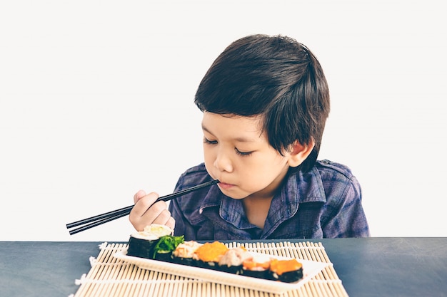 La foto di stile dell&#39;annata del ragazzo adorabile asiatico sta mangiando i sushi