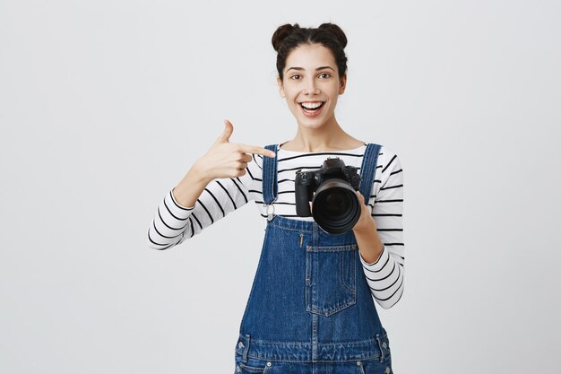 La fotografa ragazza impressionata punta il dito sul display della fotocamera, elogia gli scatti fantastici, il fantastico lavoro del modello