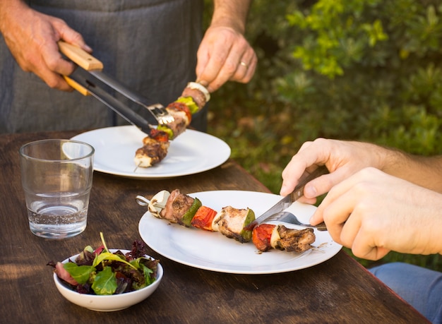 La gente che mangia barbecue cucinato in piatti sul tavolo