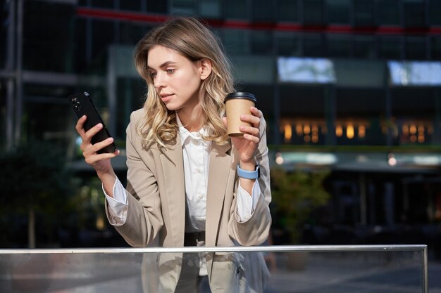 La gente d'affari giovane donna d'affari che beve caffè utilizzando l'app per smartphone che riposa durante la pausa pranzo