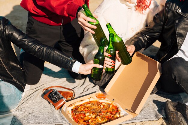 La gente tintinnio bottiglie di birra sul picnic