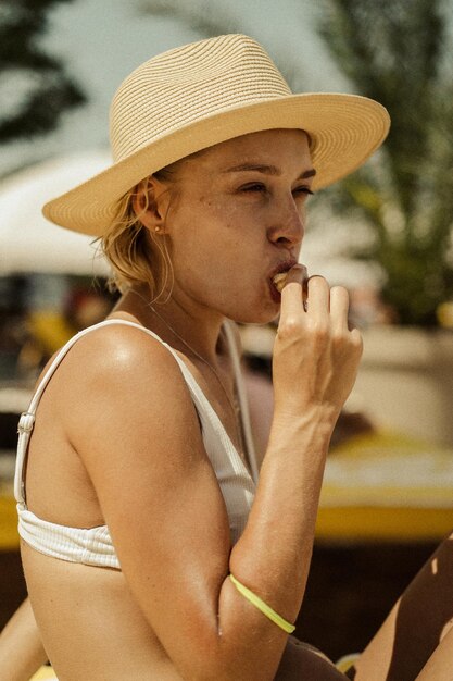 la giovane bella donna con un cappello di paglia mangia la frutta.