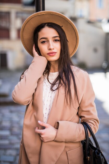 La giovane bella donna graziosa con capelli lunghi che cammina lungo la strada vestita in abiti casual autunno