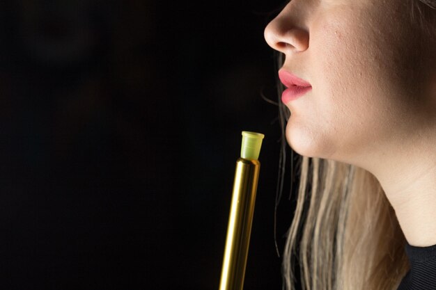 La giovane bella ragazza fuma un narghilè