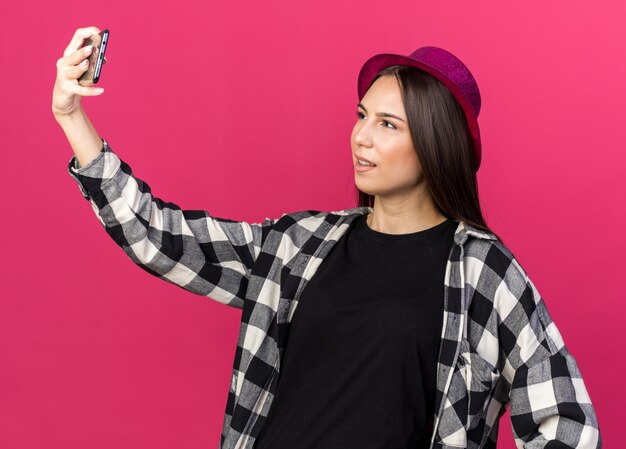 La giovane bella ragazza scontenta che indossa il cappello da festa si fa un selfie