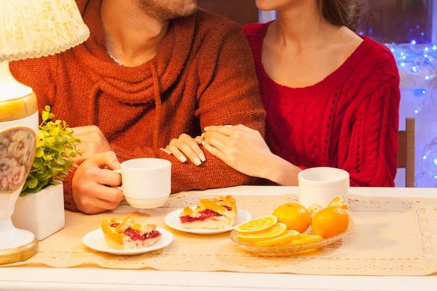 La giovane coppia felice con tazze di tè e torte.