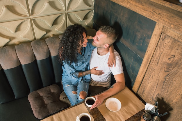 La giovane coppia felice sta bevendo il caffè e sta sorridendo mentre si sedeva al caffè