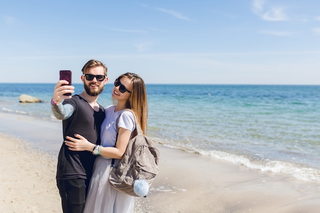 La giovane coppia sta scattando una foto del selfie vicino al mare.