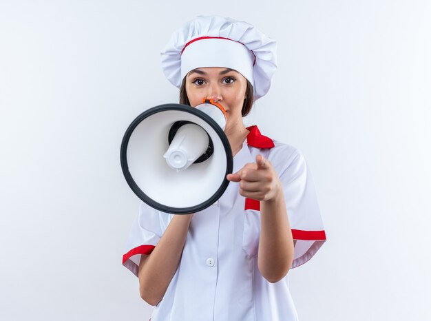 La giovane cuoca che indossa l'uniforme dello chef parla su un altoparlante isolato su sfondo bianco