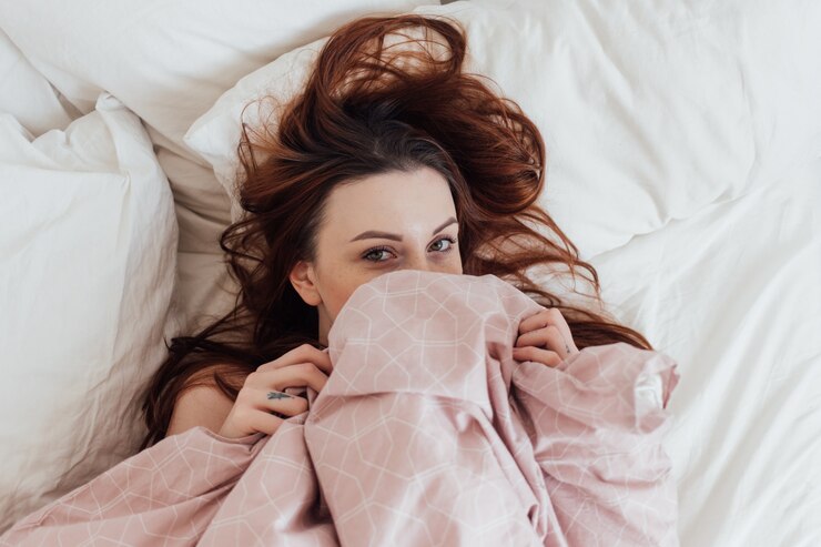 Foto gratuito la giovane donna abbastanza adorabile fa capolino dalle coperte delle lenzuola