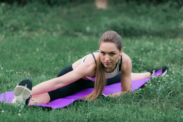 La giovane donna adatta nell&#39;abbigliamento sportivo esegue lo stretching dopo un allenamento fuori