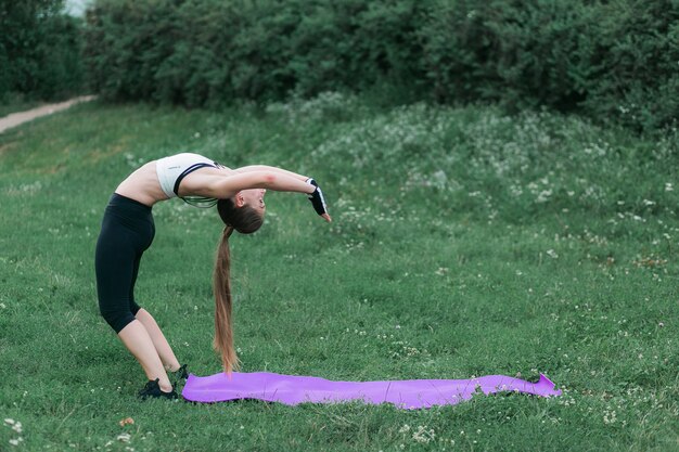 La giovane donna adatta nell&#39;abbigliamento sportivo esegue lo stretching dopo un allenamento fuori