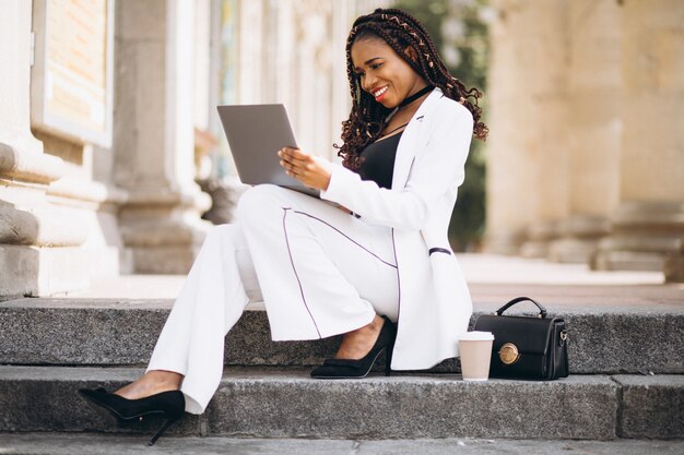 La giovane donna africana si è vestita nel bianco facendo uso del computer portatile