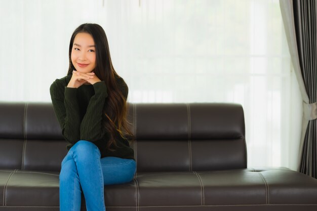 La giovane donna asiatica del bello ritratto si siede si rilassa sul sofà
