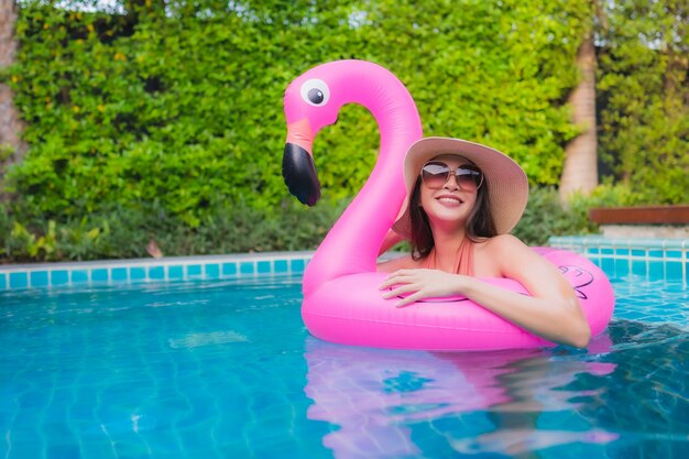 La giovane donna asiatica del ritratto si rilassa il sorriso felice intorno alla piscina in hotel