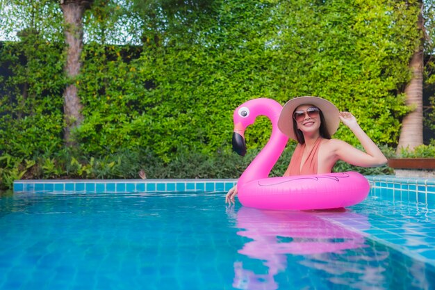 La giovane donna asiatica del ritratto si rilassa il sorriso felice intorno alla piscina in hotel