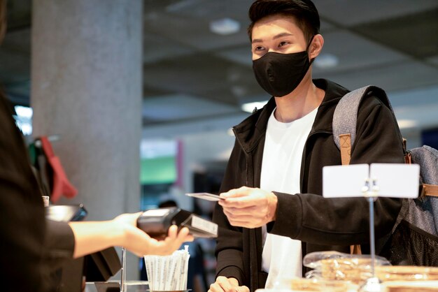 La giovane donna asiatica del viaggiatore si siede rilassa l'espressione facciale usa lo smartphone in attesa del tempo a bordo nel ristorante caffetteria al terminal delle partenze dell'aeroporto