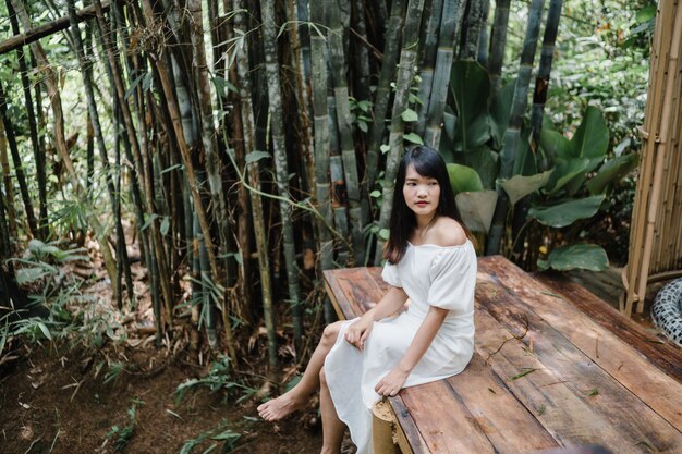 La giovane donna asiatica si rilassa in foresta, usando bello felice femminile si rilassa il tempo in natura.