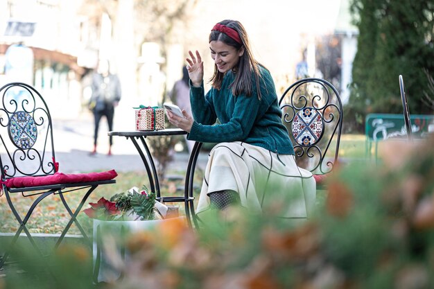 La giovane donna attraente utilizza lo shopping online di Natale dello smartphone