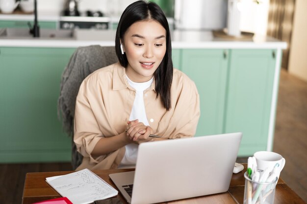 La giovane donna aziendale che lavora da casa ragazza asiatica ha lezioni online a distanza parlando in video chat...