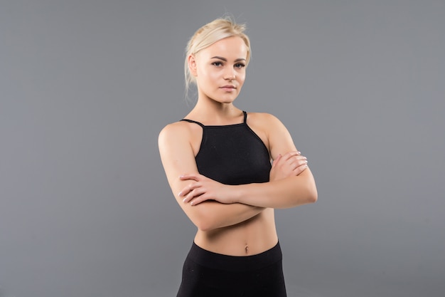 La giovane donna bionda adatta della ragazza sportiva in abiti sportivi neri dimostra il suo forte allungamento del corpo muscoloso