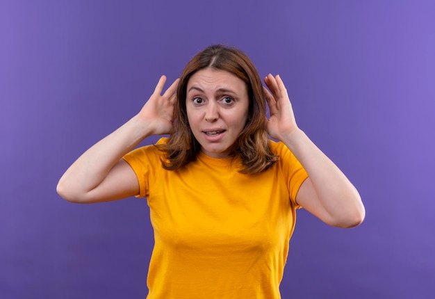 La giovane donna casuale impressionata che fa non può sentirti gesto con le mani vicino alle orecchie sullo spazio viola isolato