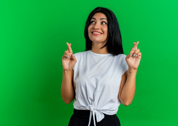 La giovane donna caucasica sorridente incrocia le dita di due mani che guardano il lato