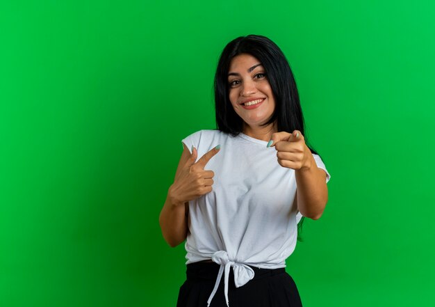 La giovane donna caucasica sorridente indica la macchina fotografica con due mani
