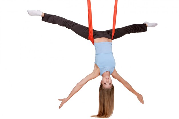 La giovane donna che fa l'yoga antigravità si esercita nell'allungamento dello spago