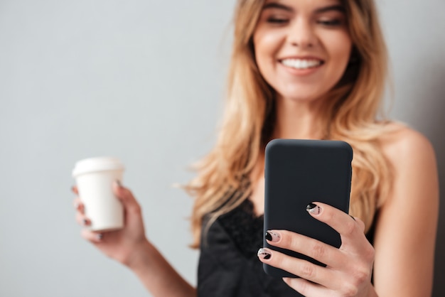 La giovane donna che per mezzo del telefono mobile e porta via la tazza