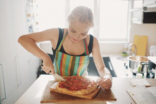 La giovane donna con un coltello ha tagliato la pizza