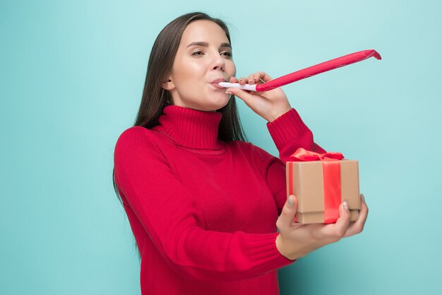 La giovane donna d'affari con un regalo che festeggia il compleanno, isolata sulla parete blu