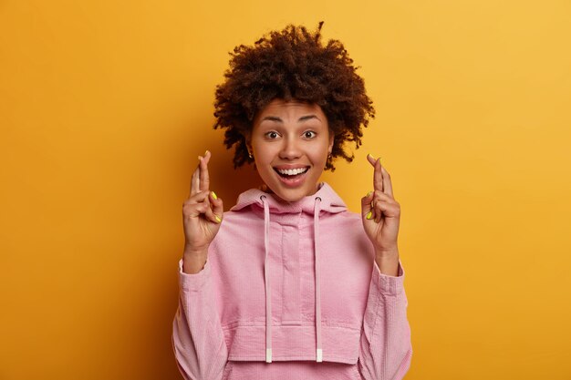 La giovane donna dalla pelle scura positiva con l'acconciatura afro guarda si spera