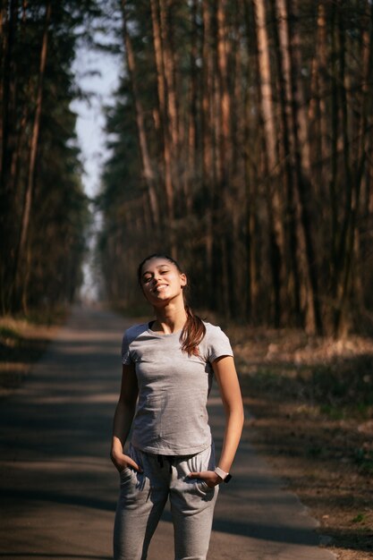 La giovane donna di forma fisica cammina nel parco e nella posa per la macchina fotografica