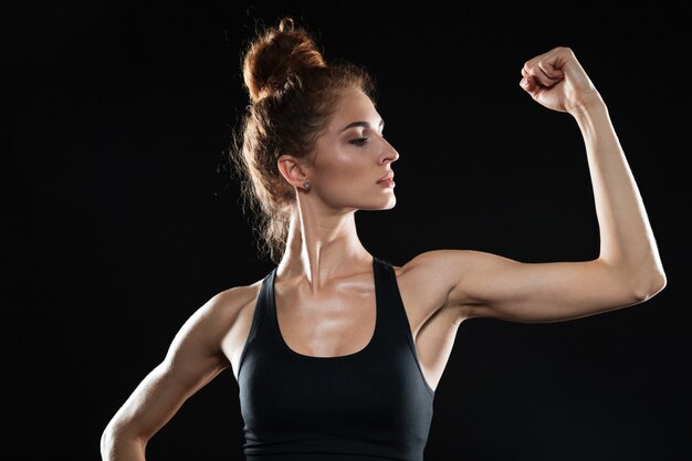 La giovane donna di sport che mostra il suo bicipite