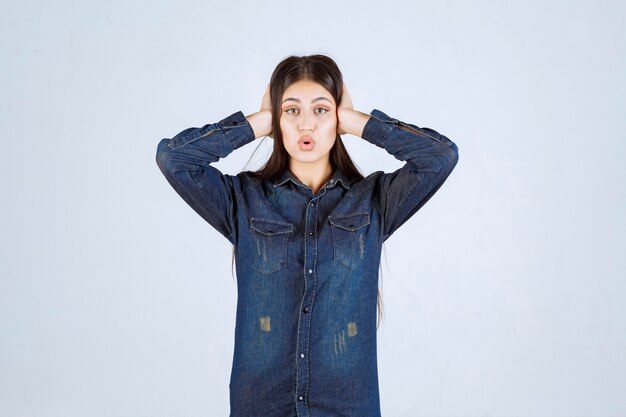 La giovane donna in camicia di jeans sembra sorpresa ed eccitata