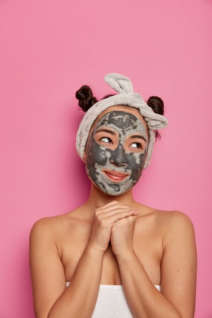 La giovane donna indossa trattamenti per la pelle della maschera di argilla facciale naturale dopo aver fatto il bagno