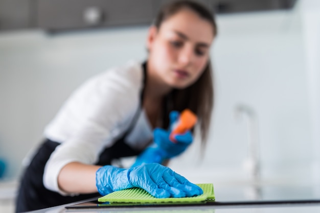 La giovane donna sorridente pulisce la cucina a casa sua